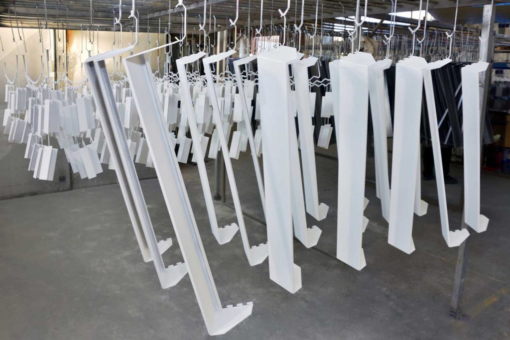 Powder-coated metal structures hung on hooks to dry